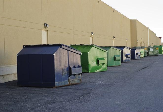 a construction worker unloading debris into a blue dumpster in Campbell